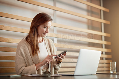 Buy stock photo Shot of a young woman working her cellphone and laptop in a cafe