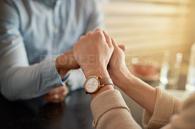 Buy stock photo Shot of an affectionate young couple holding hands while sitting in a cafe