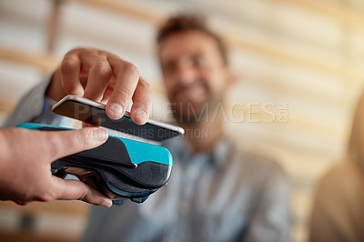 Buy stock photo Shot of a man making a payment with his cellphone using NFC technology in a cafe