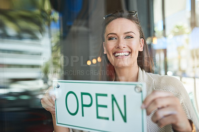 Buy stock photo Shot of a young entrepreneur holding an “open” sign in her business
