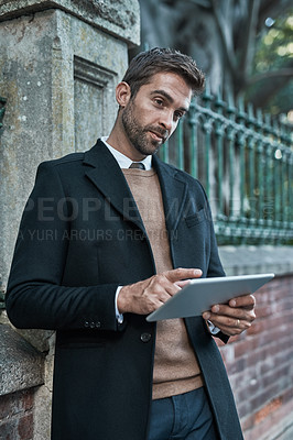 Buy stock photo Cropped shot of a handsome businessman using his tablet while about town