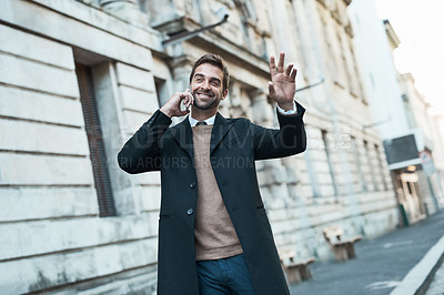 Buy stock photo Cropped shot of a handsome businessman hailing a cab while making a phonecall