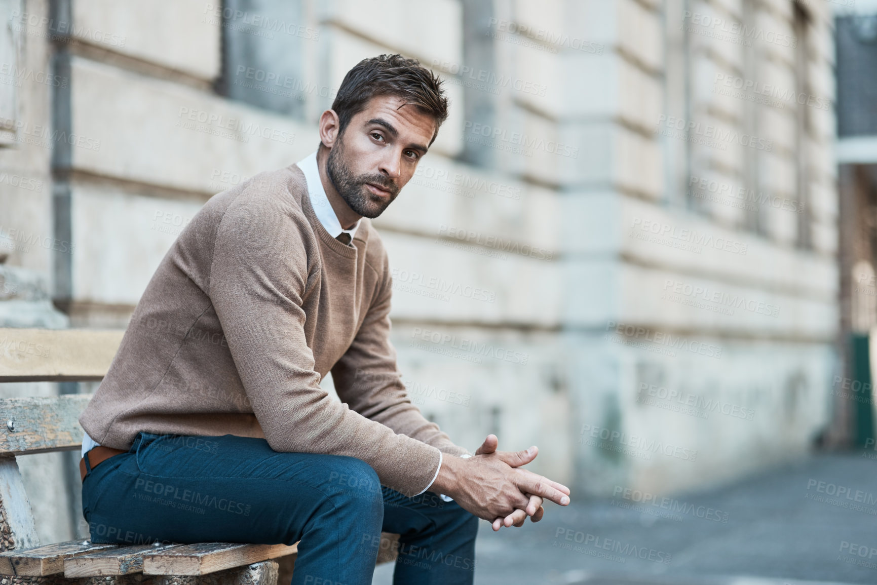 Buy stock photo Cropped portrait of a handsome businessman sitting on a bench in town