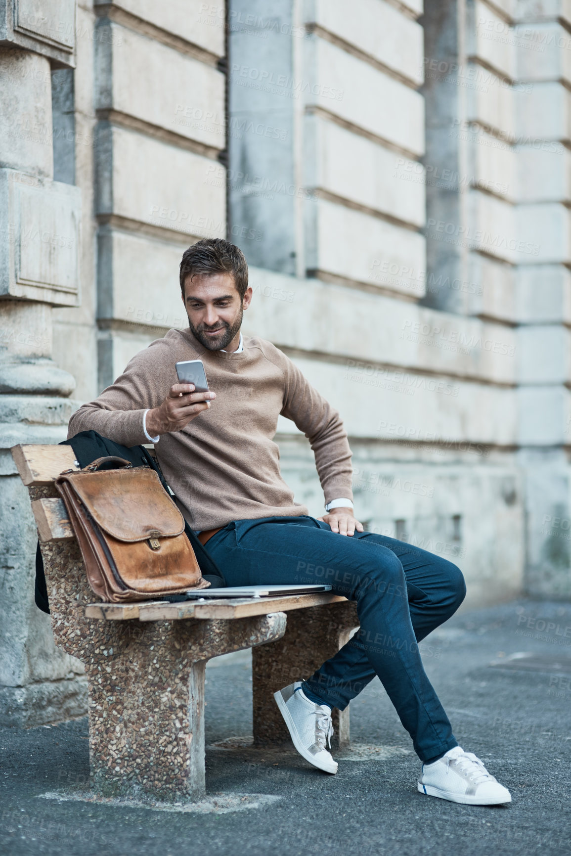 Buy stock photo Businessman, street and smile with smartphone on bench with mobile app for ehailing cab in New York. Male person, employee and happy with networking, communication and connection on social media