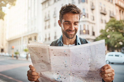 Buy stock photo Shot of a young man looking at a map while touring a foreign city