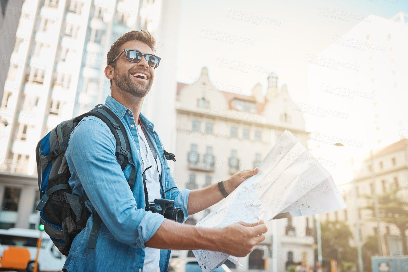 Buy stock photo Shot of a young man looking at a map while touring a foreign city