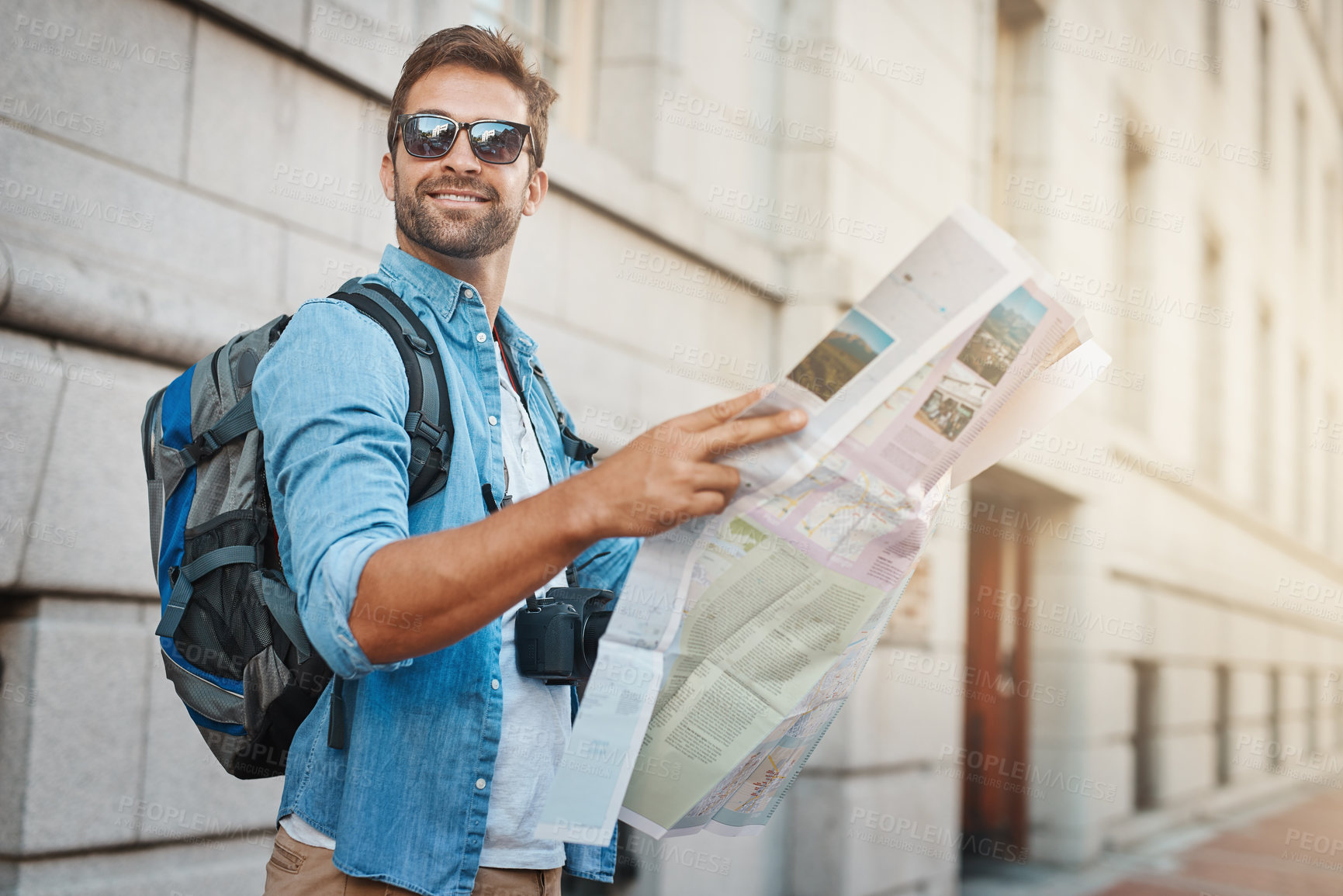 Buy stock photo Shot of a young man looking at a map while touring a foreign city
