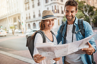 Buy stock photo Shot of a happy couple using a map while exploring a foreign city