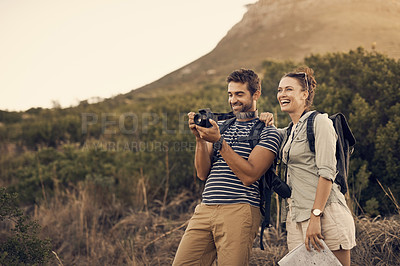 Buy stock photo Shot of a couple taking pictures on their camera while out hiking