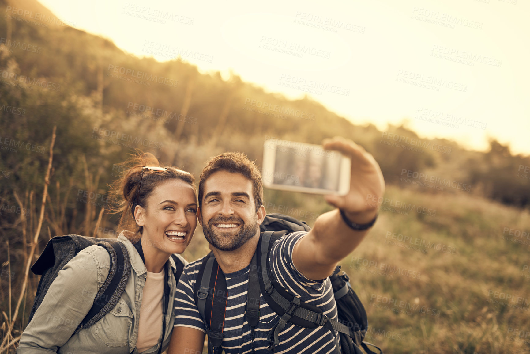 Buy stock photo Shot of a happy couple taking a selfie while out on a hiking trip