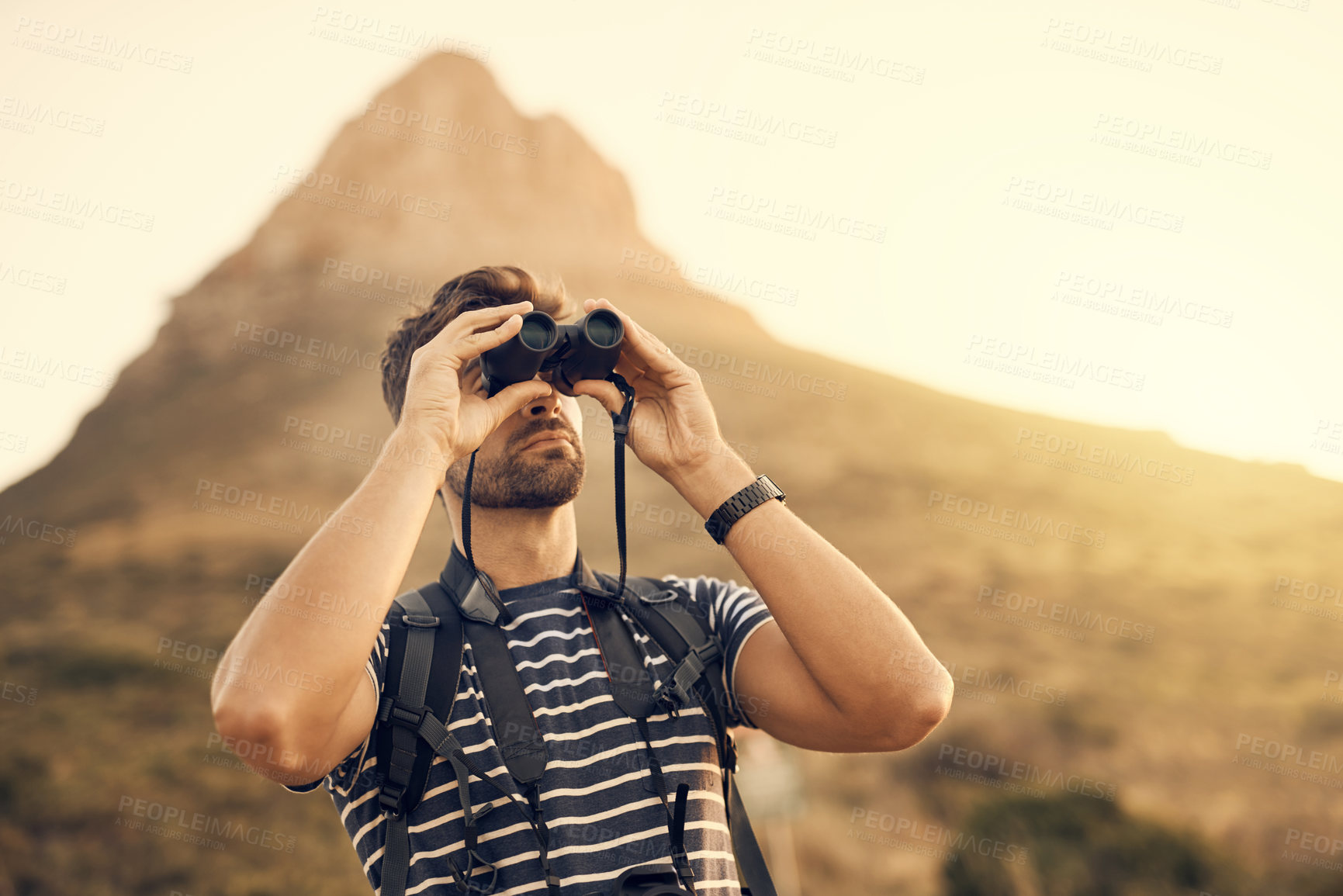 Buy stock photo Shot of a man looking through his binoculars while out hiking