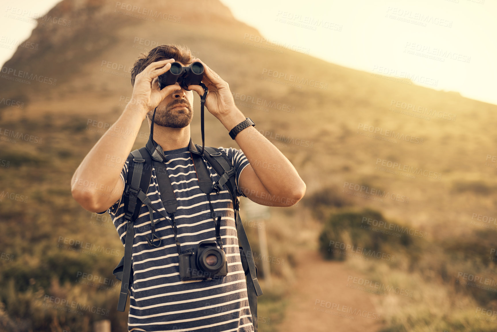 Buy stock photo Shot of a man looking through his binoculars while out hiking