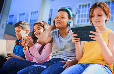 Buy stock photo Shot of a diverse group of children having fun with technology outside