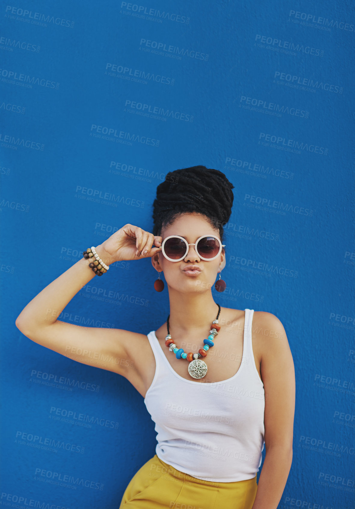 Buy stock photo Studio shot of an attractive young woman wearing funky sunglasses and pouting against a blue background