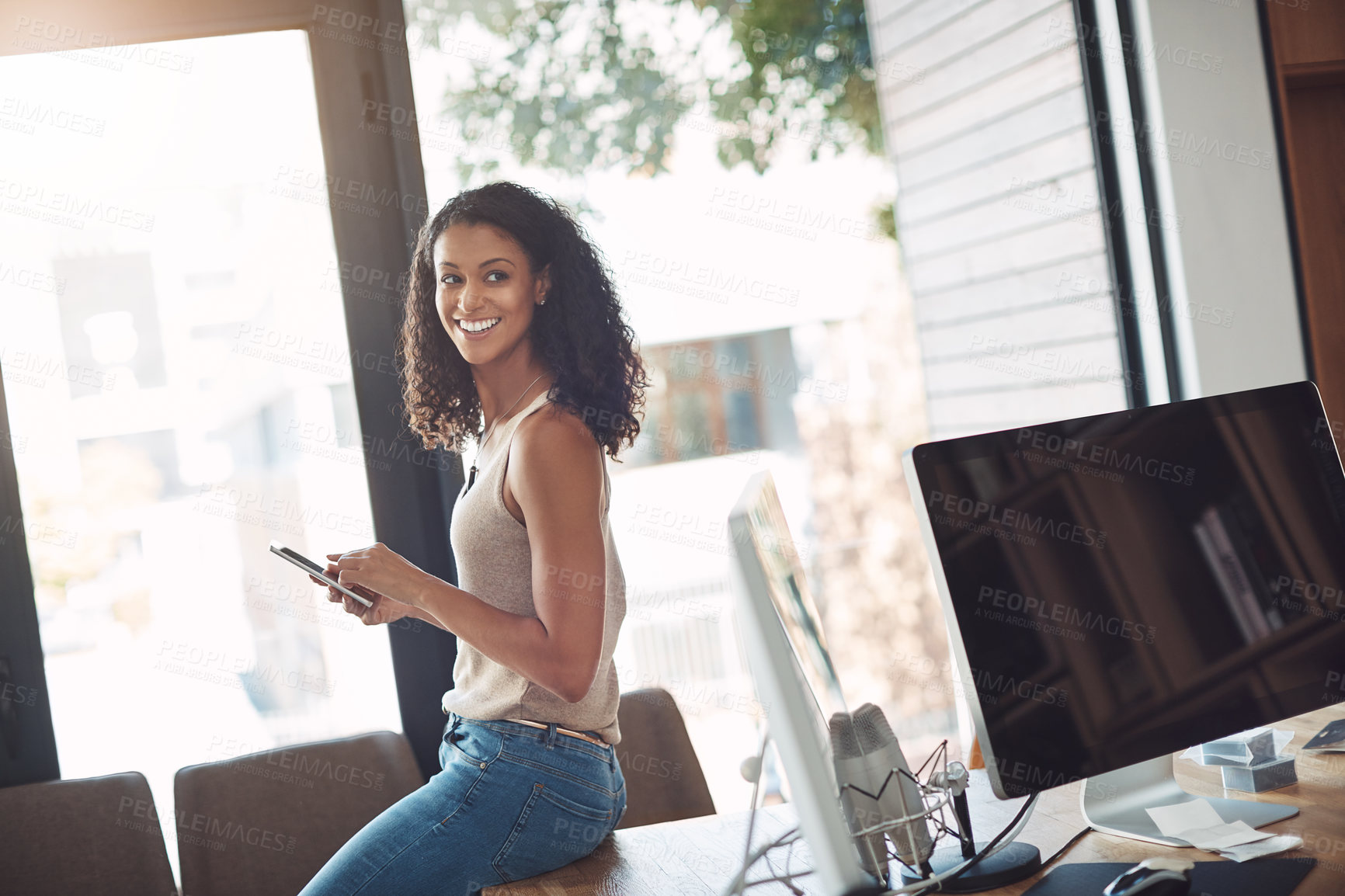 Buy stock photo Casual female holding a phone in a home office enjoying working remote sitting on her desk. Candid, real and authentic moment of digital marketing worker. Smiling woman taking a break on social media