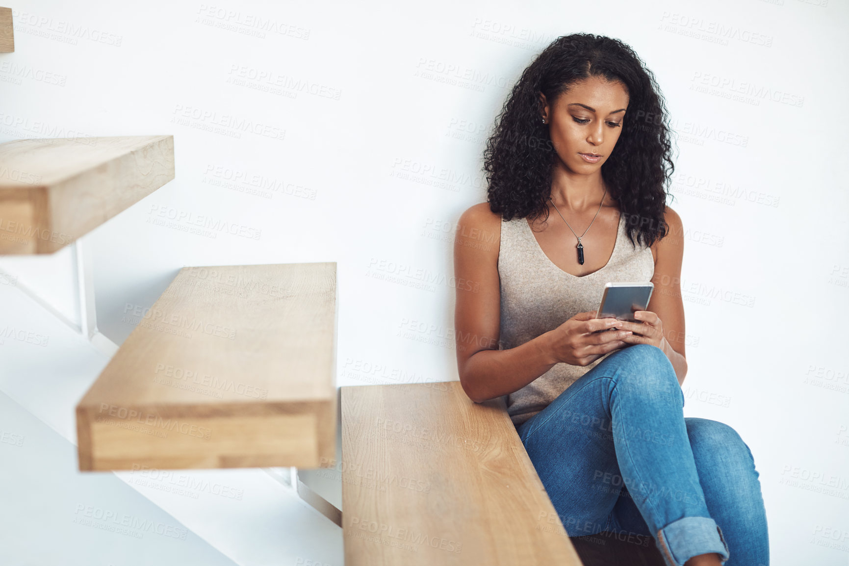 Buy stock photo Woman relaxing, looking and typing on phone sitting on wooden staircase. Attractive, casual and confident African American female reading on mobile. Taking a break and catching up on social media