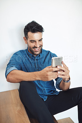 Buy stock photo Casual man relaxing, typing on a phone and browsing social media from above. Sharing information, networking and staying connected online. Updating his status and posting to his feed with an app 