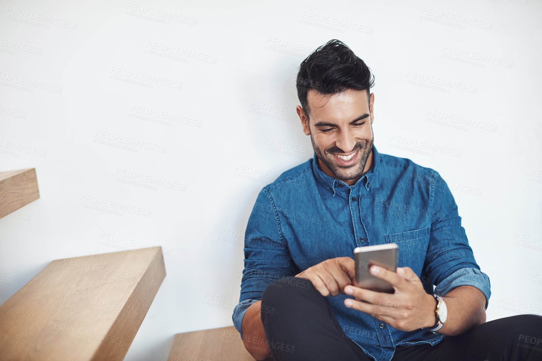 Buy stock photo Shot of a young man sitting on the stairs and using a mobile phone