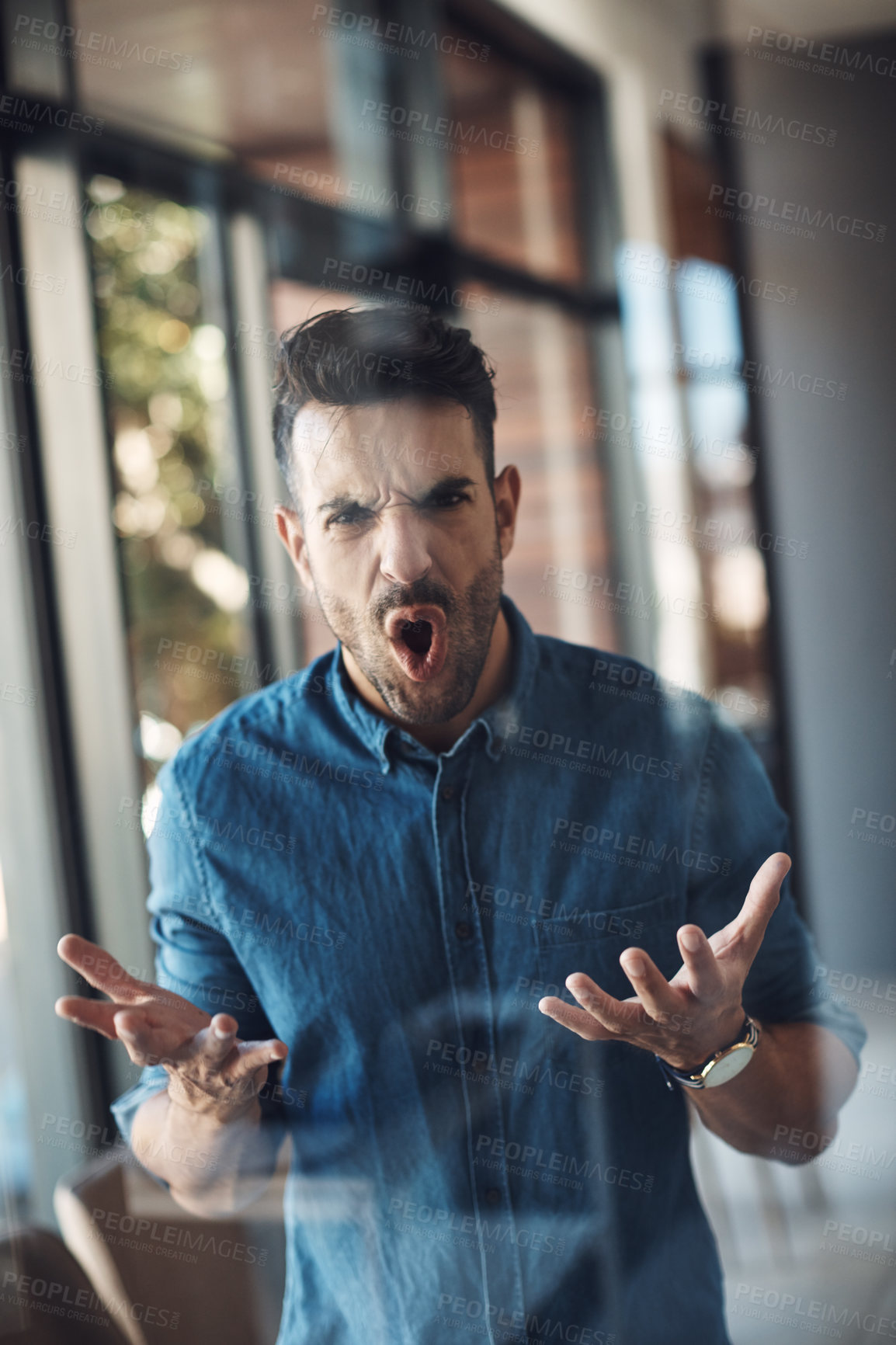 Buy stock photo Angry, stressed and frustrated man unhappy and feeling bad about work problems while standing in a modern office alone. Aggressive, annoyed and upset young male filled with emotions screaming loud

