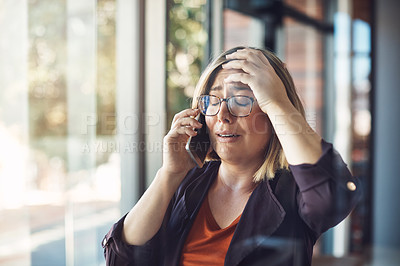 Buy stock photo Shot of a young woman looking distraught while talking on a mobile phone in a modern office