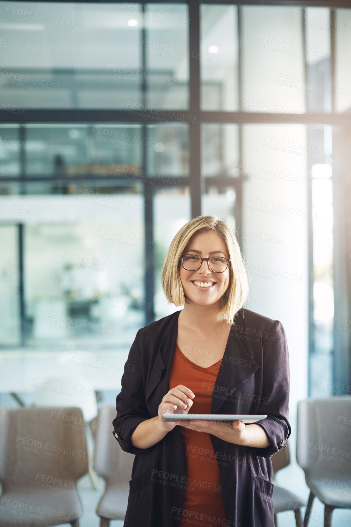 Buy stock photo Confident manager, leader or boss typing on a tablet and standing in her creative office at work. Portrait of a smiling, happy and positive business woman ready for success in her startup company