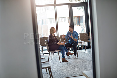 Buy stock photo Young businessman talking to his therapist after a therapy meeting at a psychology office for mental health problems. Male employee having a discussion with a mature woman in a modern boardroom
