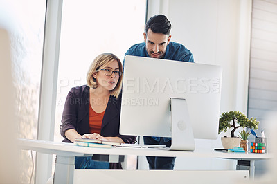 Buy stock photo Shot of a young man and woman using a computer together in a modern office
