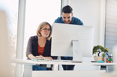 Buy stock photo Shot of a young man and woman using a computer together in a modern office