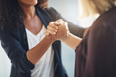 Buy stock photo Cropped shot of two businesswomen shaking hands in solidarity at work