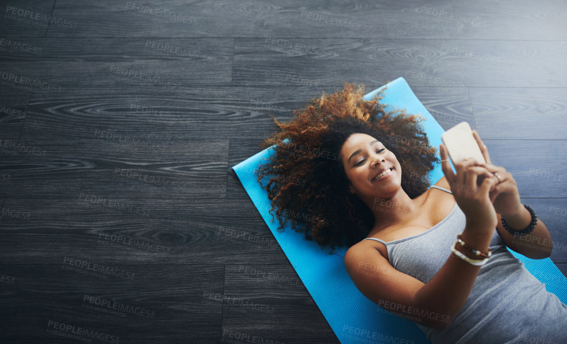 Buy stock photo Laugh, phone and yoga mat with African woman, smile and wellness studio for pilates. Social media, space and above on floor with break, health and web search for online exercise class with tech