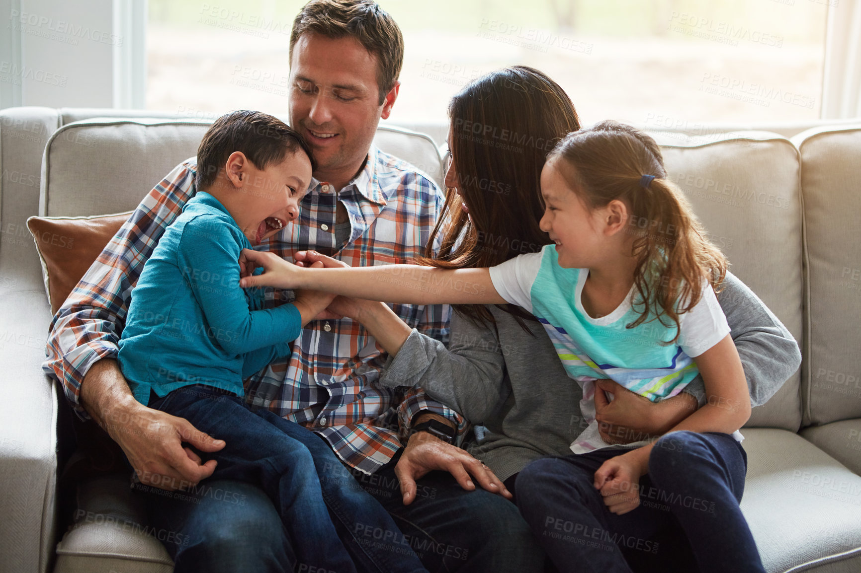 Buy stock photo Laughing, children and happy family in home with parents together for care, love or bonding. Kids, mother and father on sofa for support, relax and playing with funny siblings tickle in living room