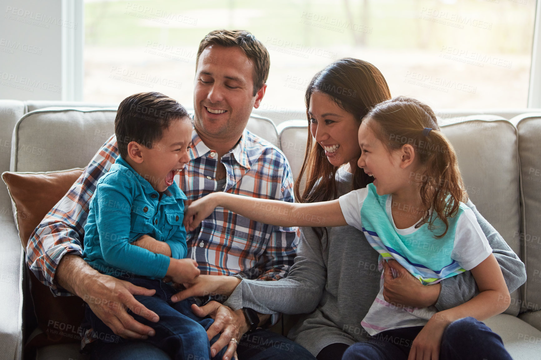 Buy stock photo Tickle, kids and happy family in home with parents together for care, love and bonding. Children, mother and father on sofa for support, relax and playing with funny siblings laughing in living room