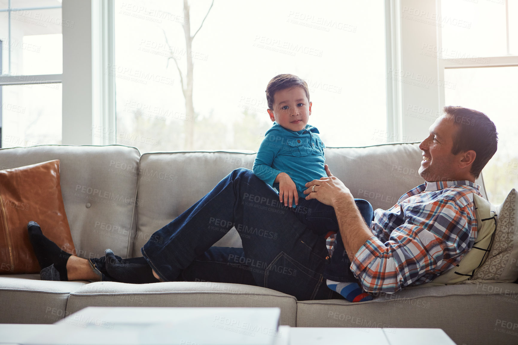 Buy stock photo Shot of an adorable little boy and his father playing together on the sofa at home