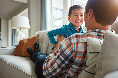 Buy stock photo Shot of an adorable little boy and his father playing together on the sofa at home