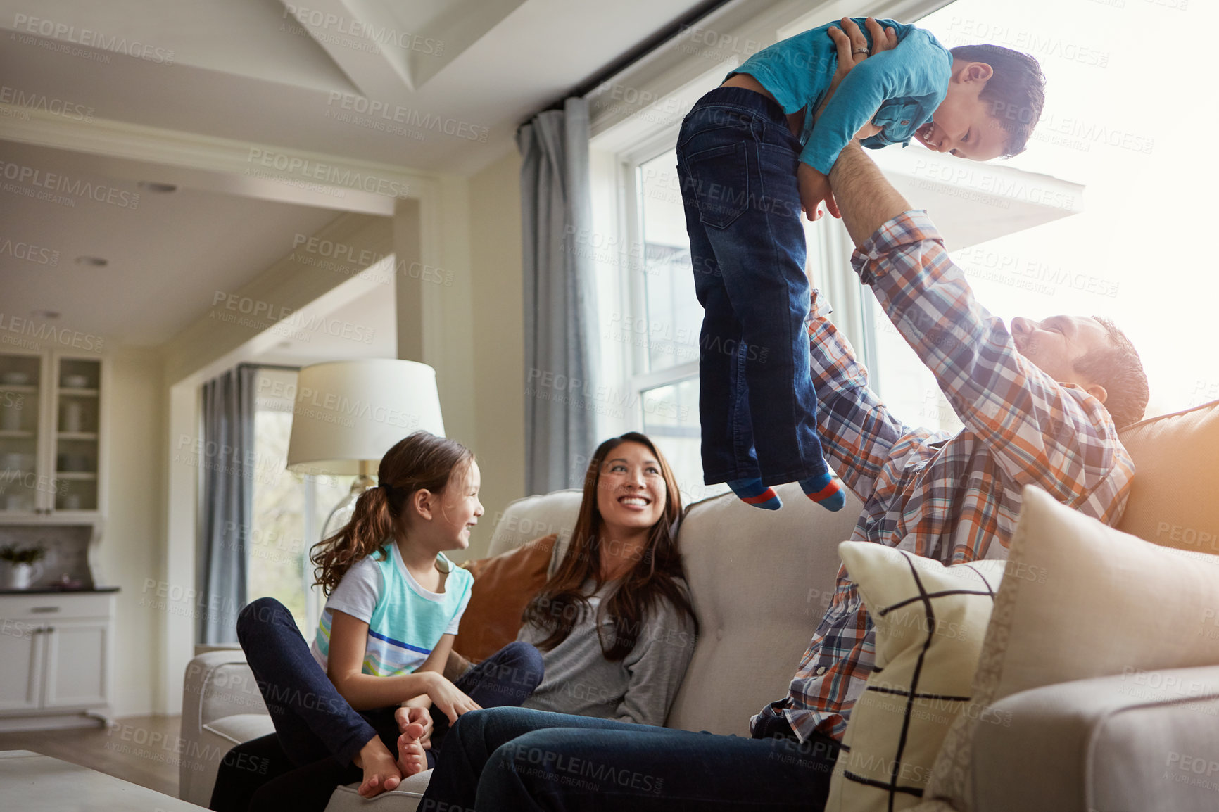 Buy stock photo Shot of a happy young family of four bonding together on the sofa at home