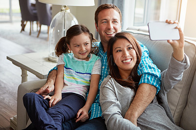 Buy stock photo Interracial parents, child and selfie on couch for smile, hug and relax with care, diversity or memory in home. Father, mother and daughter on sofa for embrace, social media or love in family house