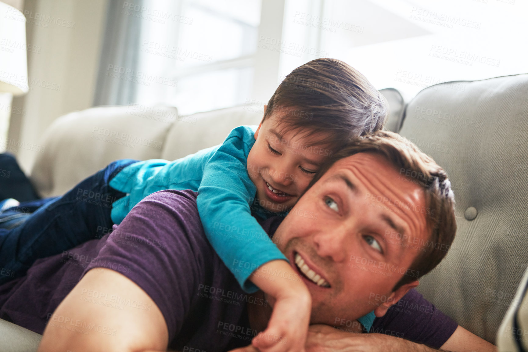 Buy stock photo Shot of an adorable little boy and his father playing together on the sofa at home