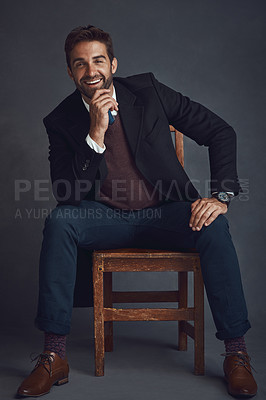 Buy stock photo Studio portrait of a stylishly dressed young man sitting on a chair against a gray background