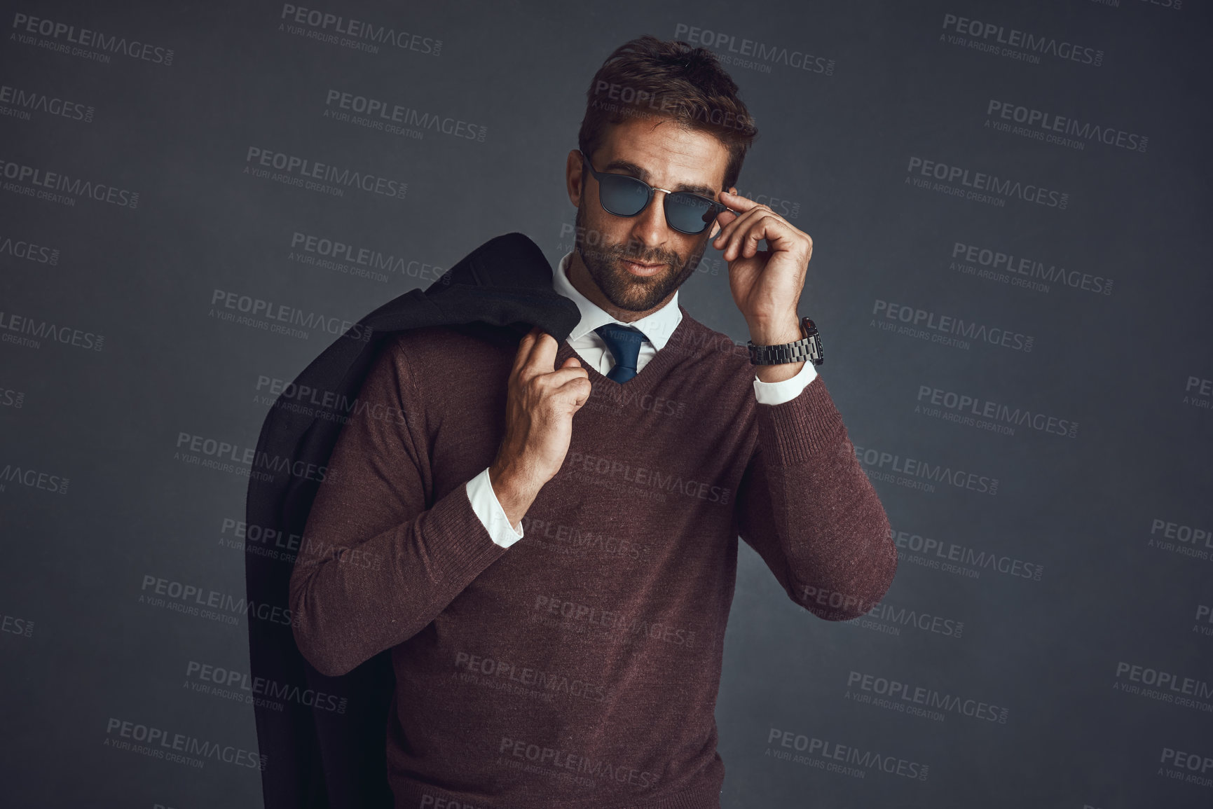 Buy stock photo Studio portrait of a stylishly dressed young man carrying his jacket against a gray background
