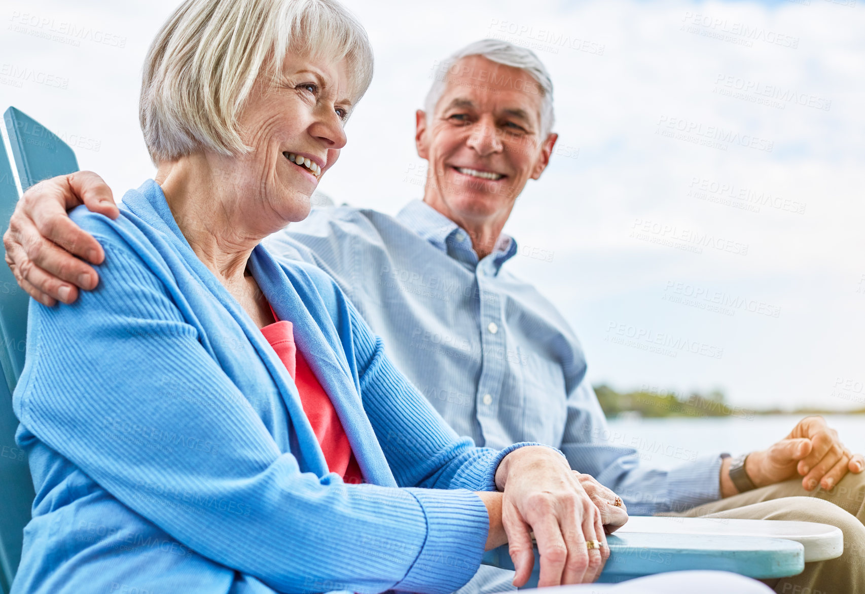 Buy stock photo Shot of an affectionate senior couple relaxing on chairs together outside