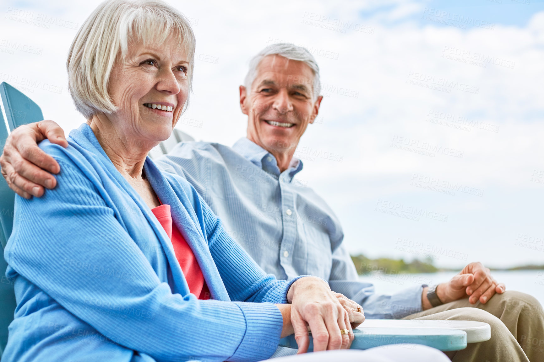 Buy stock photo Shot of an affectionate senior couple relaxing on chairs together outside