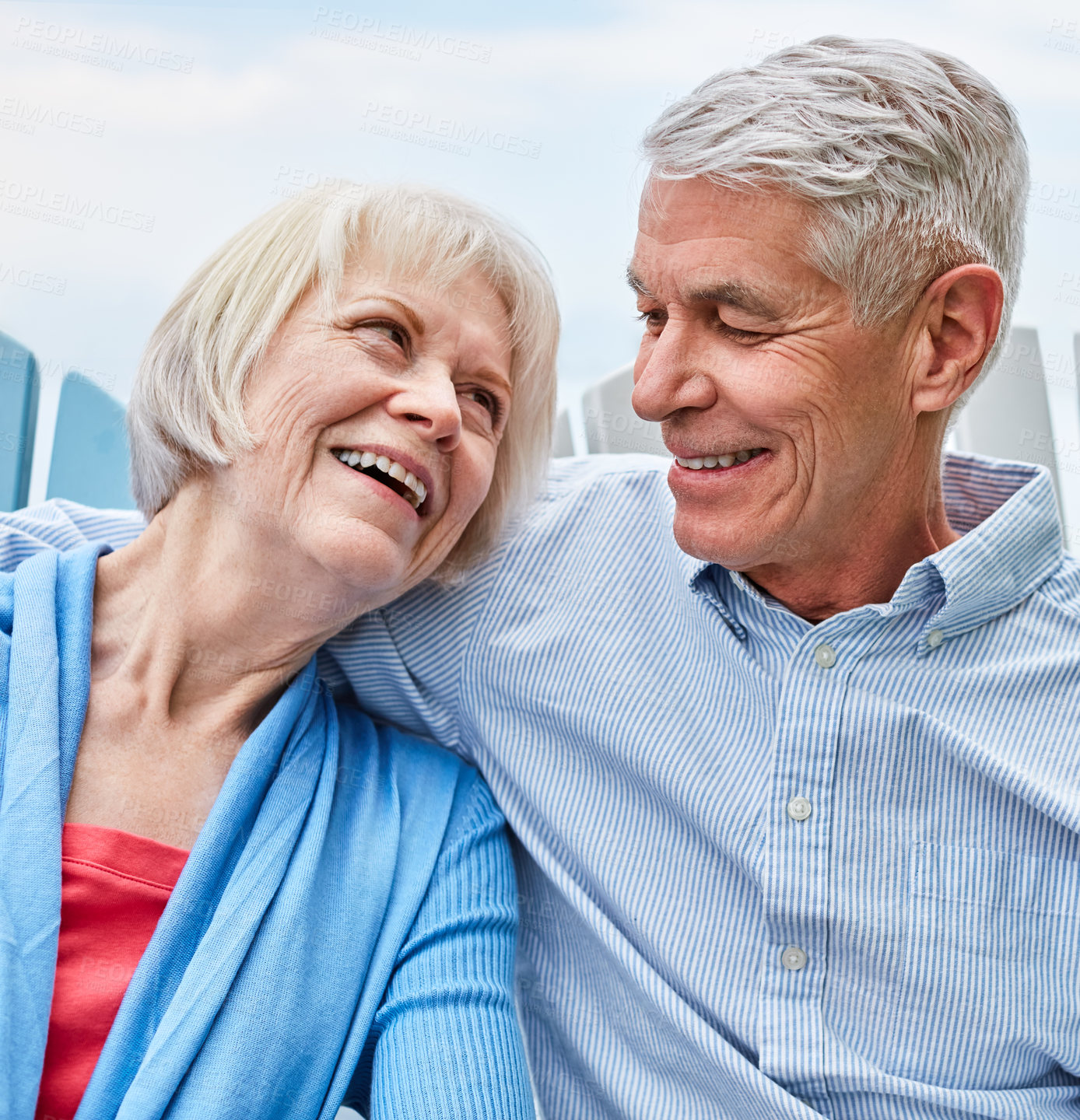 Buy stock photo Shot of an affectionate senior couple relaxing on chairs together outside