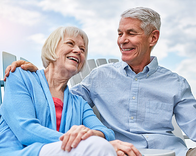 Buy stock photo Shot of an affectionate senior couple relaxing on chairs together outside