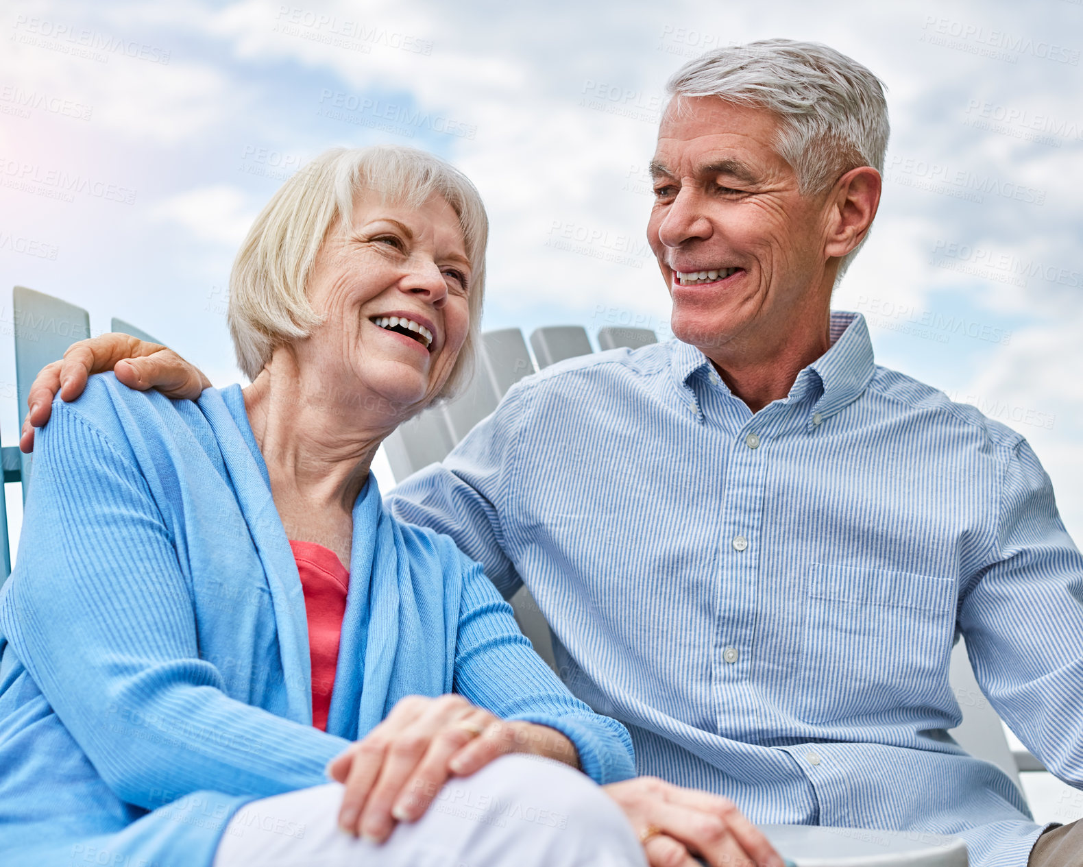 Buy stock photo Shot of an affectionate senior couple relaxing on chairs together outside