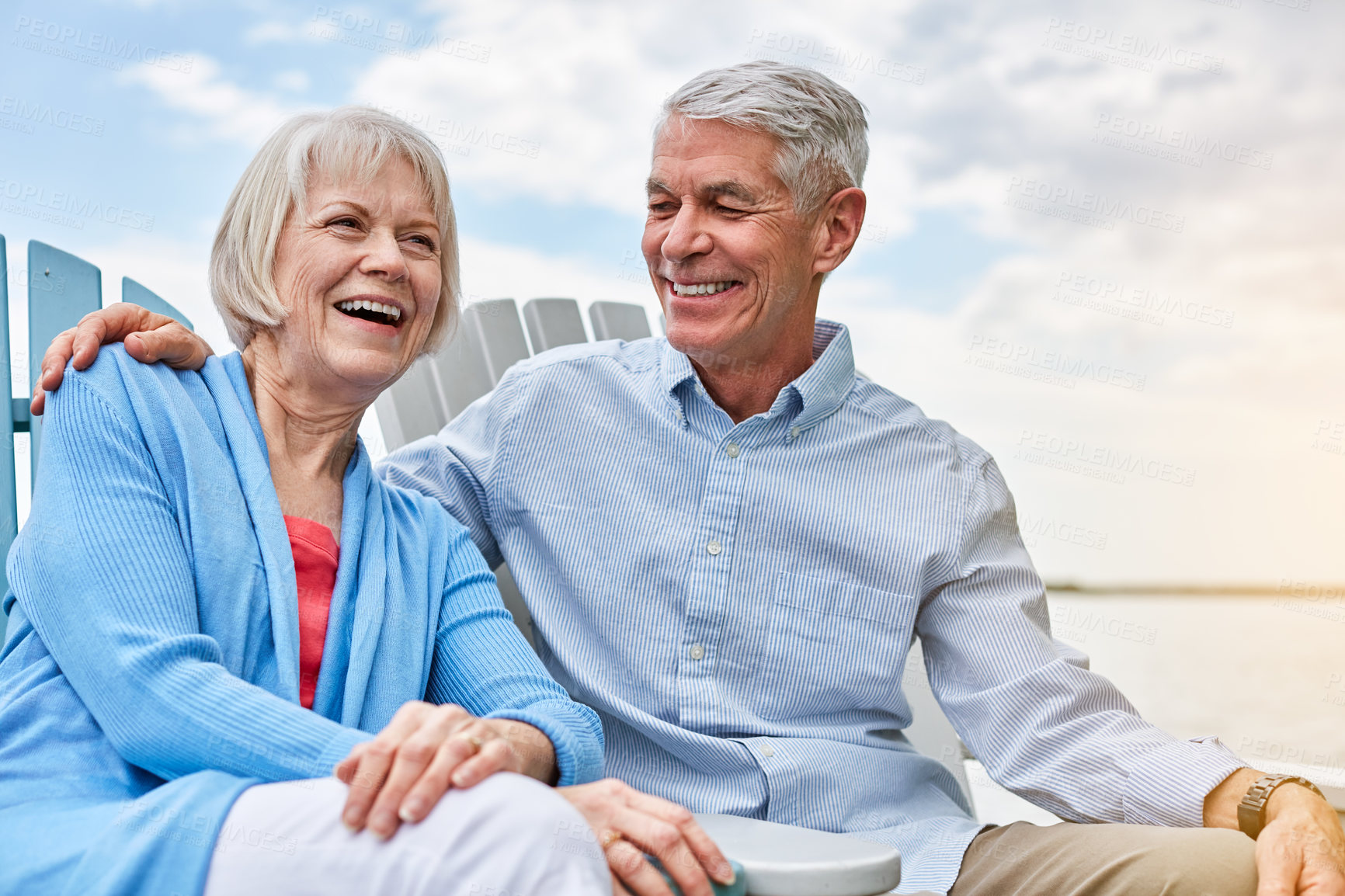 Buy stock photo Shot of an affectionate senior couple relaxing on chairs together outside