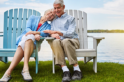 Buy stock photo Shot of an affectionate senior couple relaxing on chairs together outside