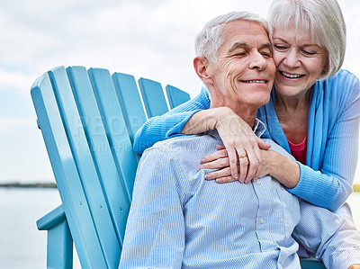 Buy stock photo Shot of an affectionate senior couple relaxing on chairs together outside