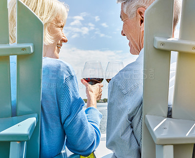 Buy stock photo Shot of a happy senior couple relaxing together outside and toasting with wine