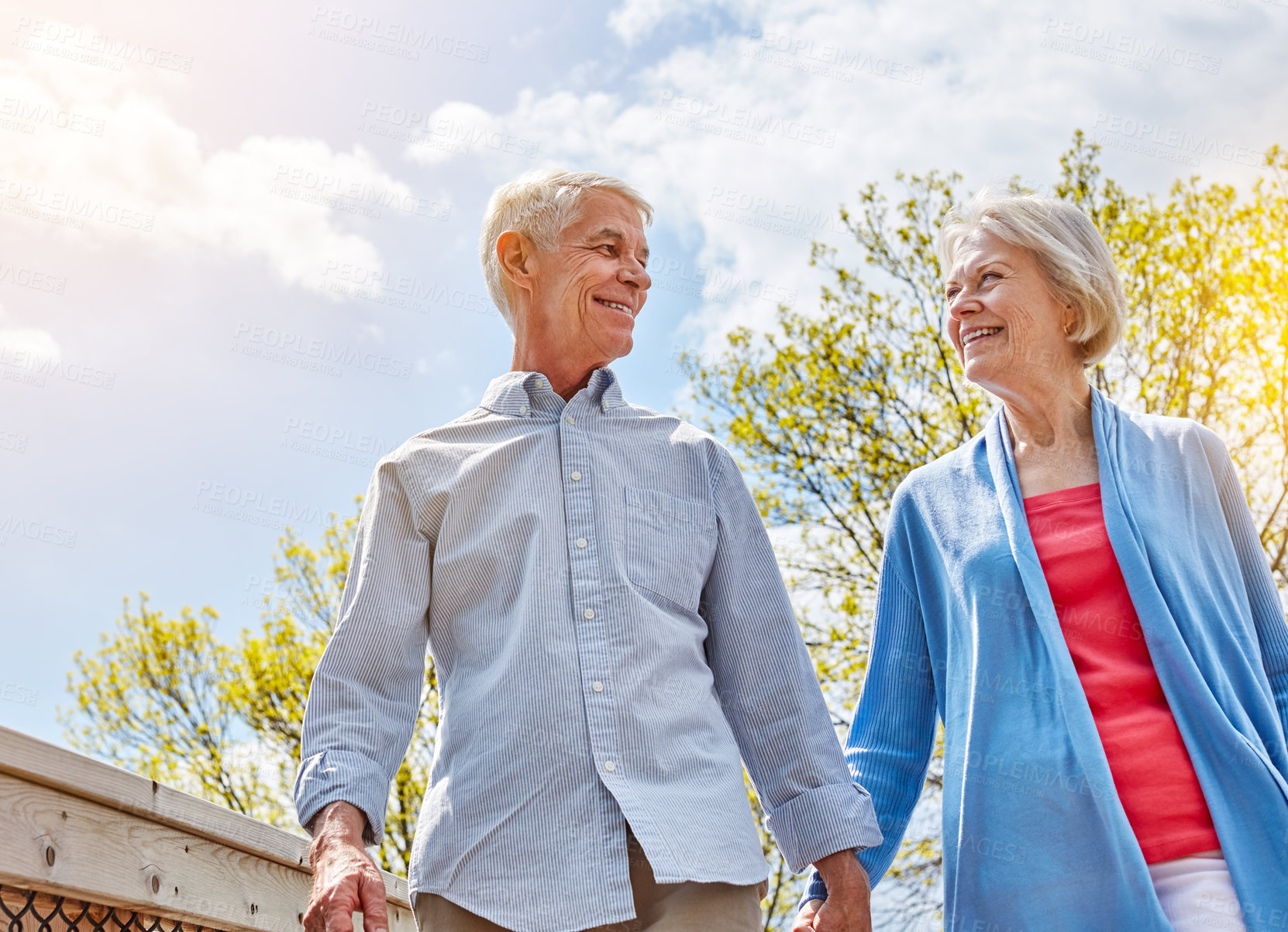 Buy stock photo Smile, senior couple and holding hands for love, bonding together and low angle on holiday. Connection, elderly man and woman outdoor for vacation, care or loyalty for marriage at park in retirement