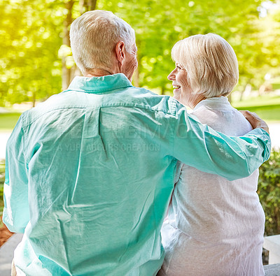 Buy stock photo Rearview shot of an affectionate senior couple sitting outside on their porch during the summer